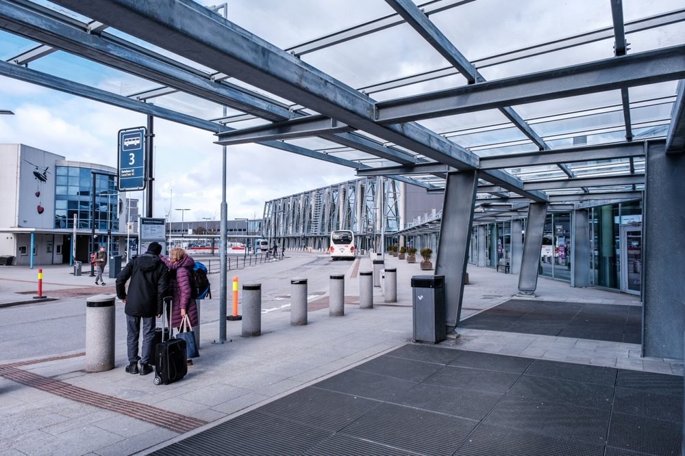 Terminal forecourt at Stavanger Airport Sola with travellers, luggage and a bus stop outside the entrance